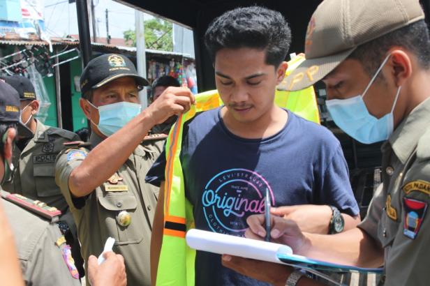 Petugas Satpol PP Padang memasangkan rompi kepada masyarakat yang melanggar Protokoler Kesehatan