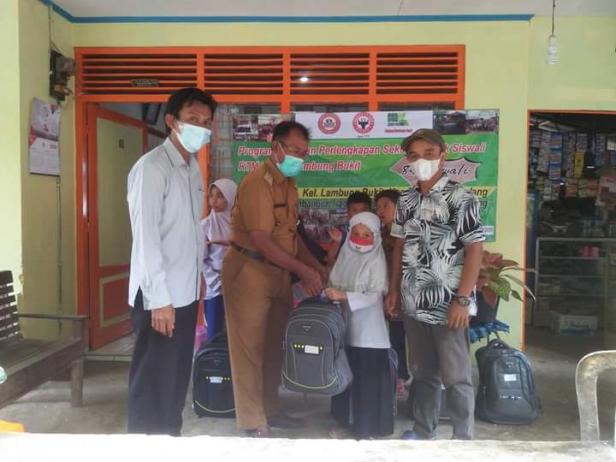 Lurah Lambung Bukit Yusrizal (dua dari kiri), menyerahkan bantuan paket pendidikan dari PT Semen Padang kepada salah satu pelajar dari RTM di Lambung Bukit.