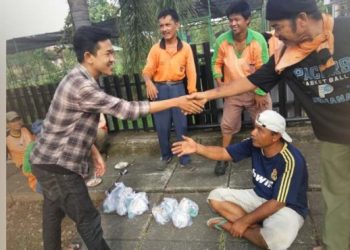 Salah seorang anggota dari FMC menyerahkan sarapan kepada pekerja kebersihan di Padang.