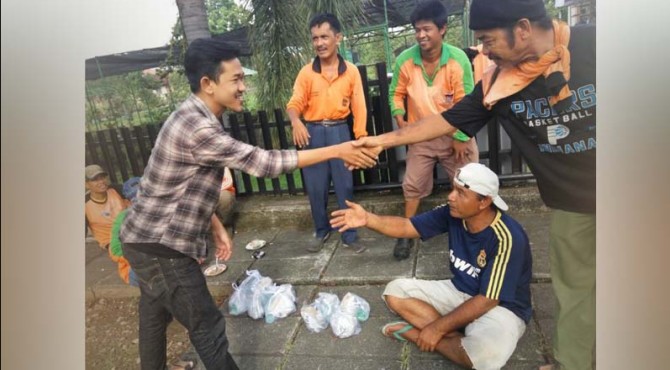 Salah seorang anggota dari FMC menyerahkan sarapan kepada pekerja kebersihan di Padang.