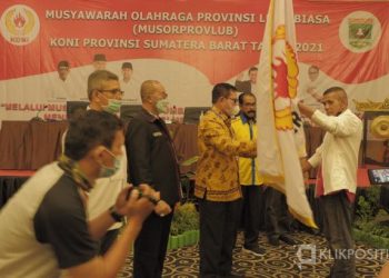 Agus Suardi menerima bendera pataka KONI dari pimpinan sidang, Syahrial Bakhtiar