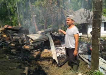 Bambang Sugiatno tengah menyaksikan sisa puing-puing kebakaran kandang kambing miliknya.