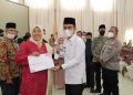 Dr. Ramadhani Kirana Putra menyerahkan piagam dan piala ibu hebat dan lomba PKK serta GOW Kota Solok