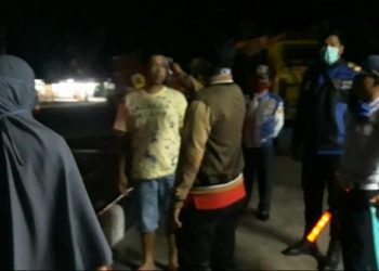 Personil Gugus Tugas memeriksa suhu tubuh warga di malam hari