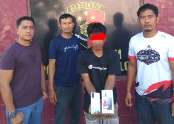 Pelaku pencurian menunjukkan handphone hasil curiannya usai tertangkap tim Unit Reskrim Polsek Solok Kota.(Ist)