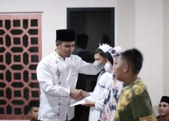 Bahagia, Wakil Wali Kota Solok tampak senang saat menyerahkan santunan bagi anak yatim di lingkungan Masjid Nurul Huda Tembok.(Prokomp)