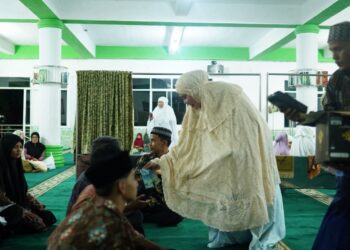 Ketua TP-PKK Kabupaten Solok, Ny. Emiko Epyardi Asda menyerahkan santunan dan kain sarung bagi anak yatim di Masjid Ikhlas Ar-Rahman Kayu Aro.(Ist)