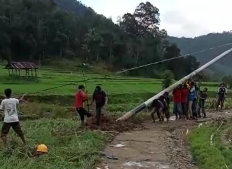 Petugas PLN dan warga mendirikan kembali tiang listrik yang roboh pasca banjir bandang.(Ist)