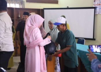 Ketua TP PKK Kota Solok, Hj. Zulmiyetti Zul Elfian menyerahkan paket lebaran kepada masyarakat penerima.(Prokomp)