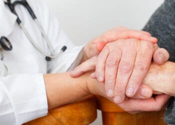 Photo of a caregiver hand touching elderly patients hand