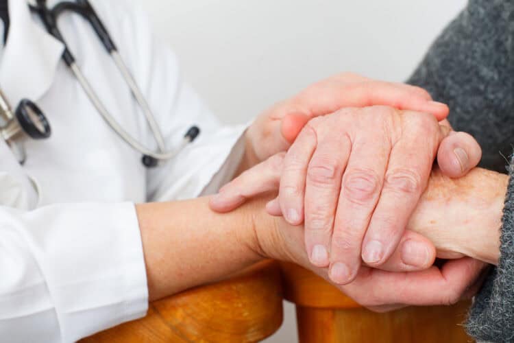 Photo of a caregiver hand touching elderly patients hand