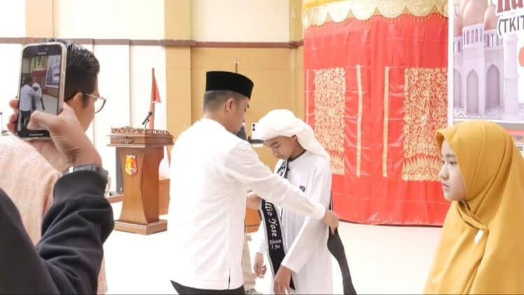 Wakil Wali Kota Solok, Dr. Ramadhani Kirana Putra memasangkan selempang tanda wisuda tahfiz kepada salah seorang peserta.(Prokomp)