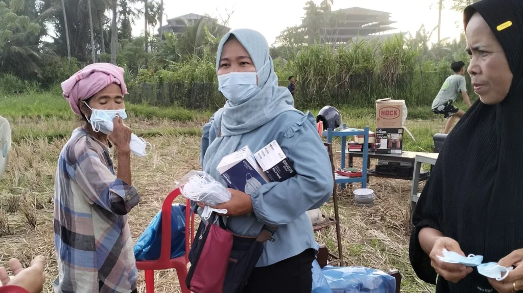 Petugas Puskesmas membagikan masker pada warga yang berada dekat bangunan pabrik karet yang terbakar