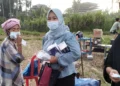 Petugas Puskesmas membagikan masker pada warga yang berada dekat bangunan pabrik karet yang terbakar
