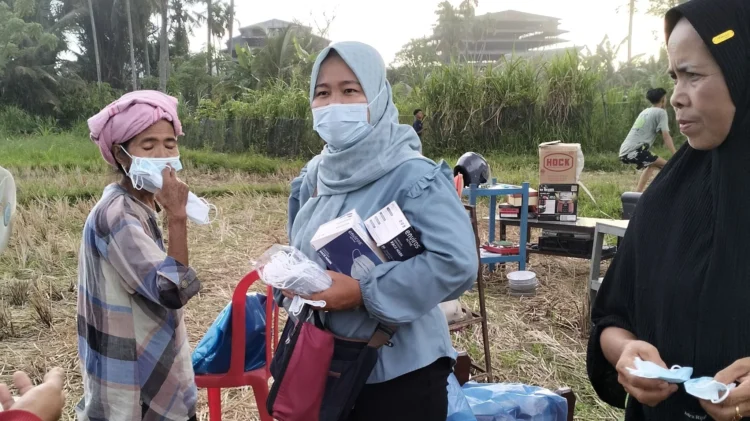 Petugas Puskesmas membagikan masker pada warga yang berada dekat bangunan pabrik karet yang terbakar