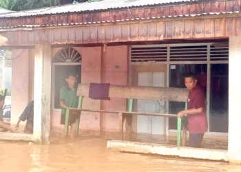 Adra Yusti Apri Amte saat mengevakuasi peralatan warga terdampak Banjir di Kampung Koto Baru, Kamis (27/11/2025).
