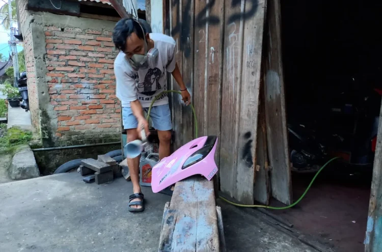 Yogi mengecat part motor di bengkel cat sederhana yang mulai dirintisnya sejak tahun lalu